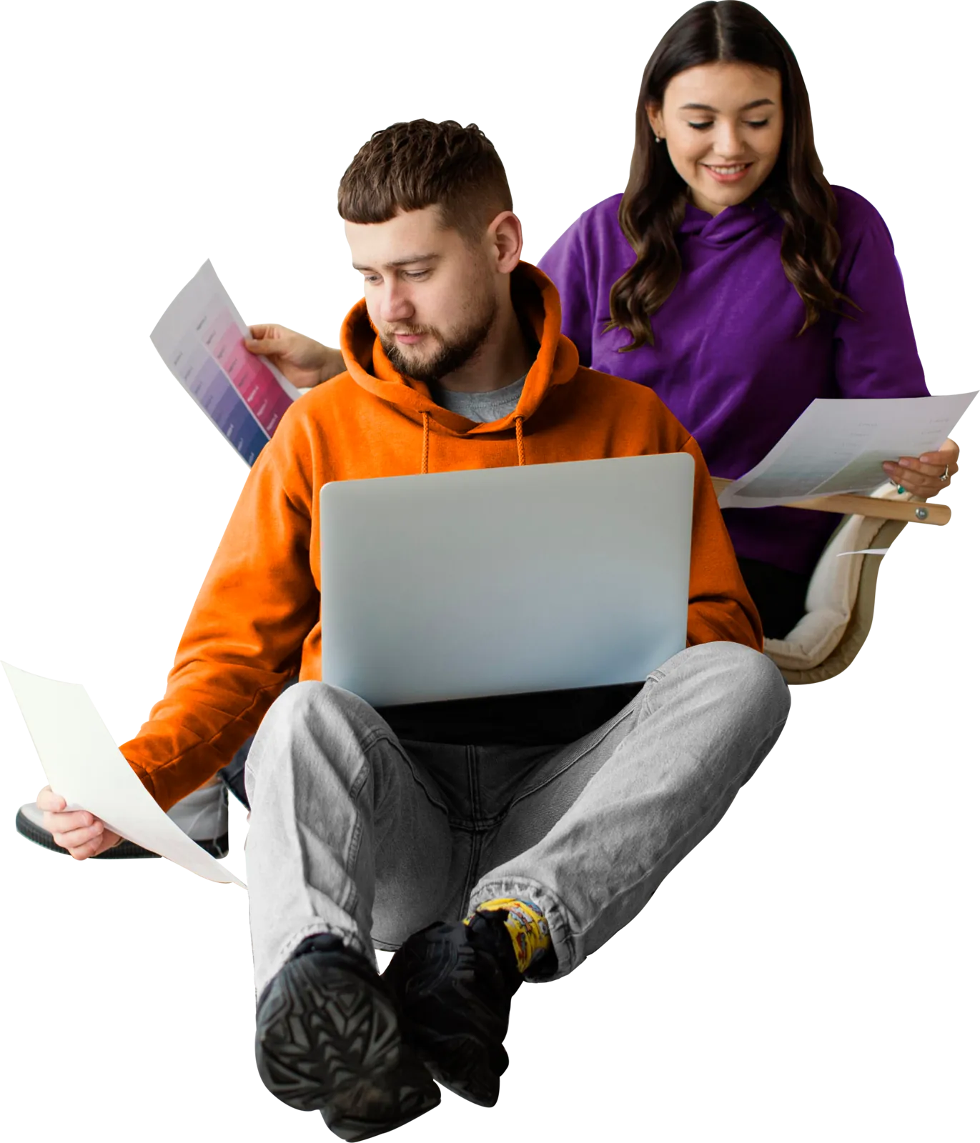 Two students studying together, one working on a laptop while the other reviews her notes